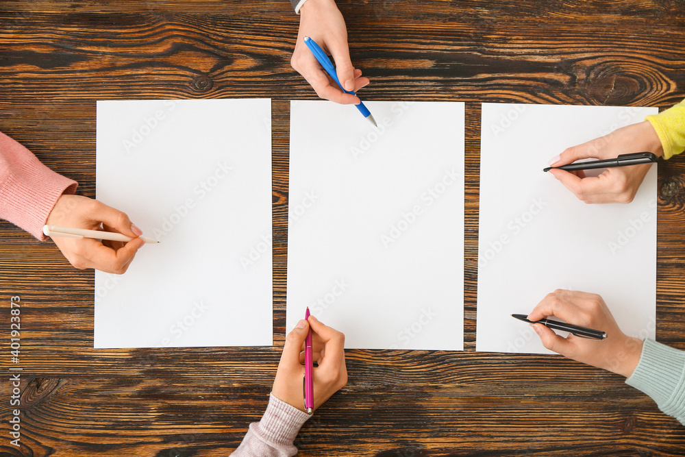 People hands with blank papers on wooden background People hands with blank papers on wooden background
