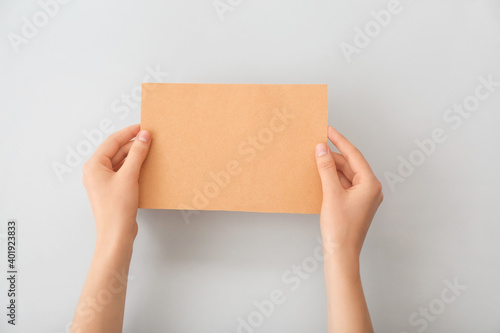 Female hands with blank paper on light background © Pixel-Shot