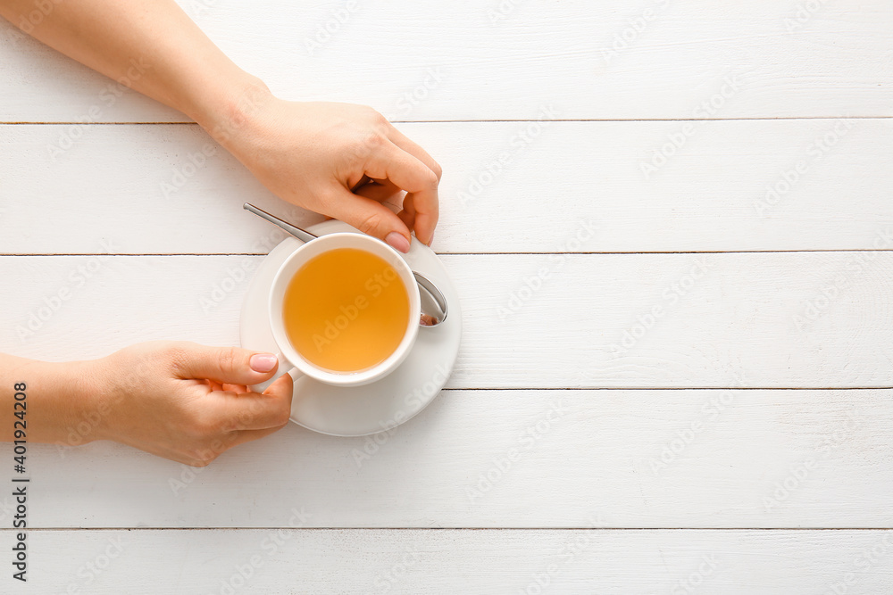 Female hands with cup of green tea on wooden table Female hands with cup of green tea on wooden table