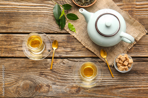 Composition with cups of green tea and teapot on wooden table