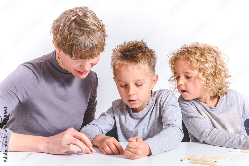 family of caucasian blond mother, boy and girl drawing together on a white desk with white background family of caucasian blond mother, boy and girl drawing together on a white desk with white background