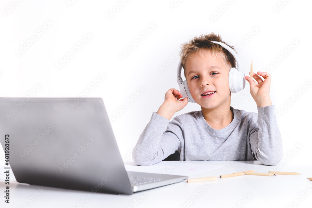 blond caucasian boy home schooling with headphones and laptop and looking to camera blond caucasian boy home schooling with headphones and laptop and looking to camera