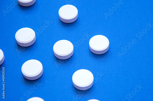Set of white pills on blue background. Pills background. White tablets on a blue background