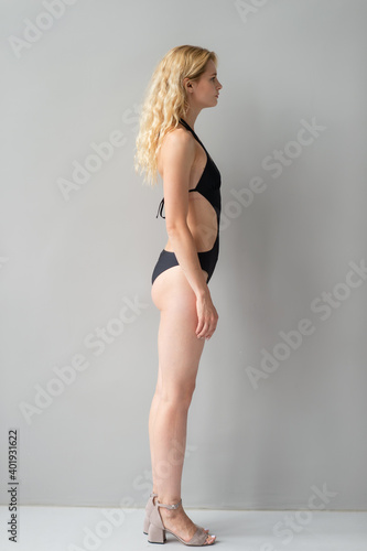 Attractive young blonde model in black swimsut posing in studio
