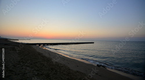 the sun rises early in the morning and illuminates the sea and the old pier