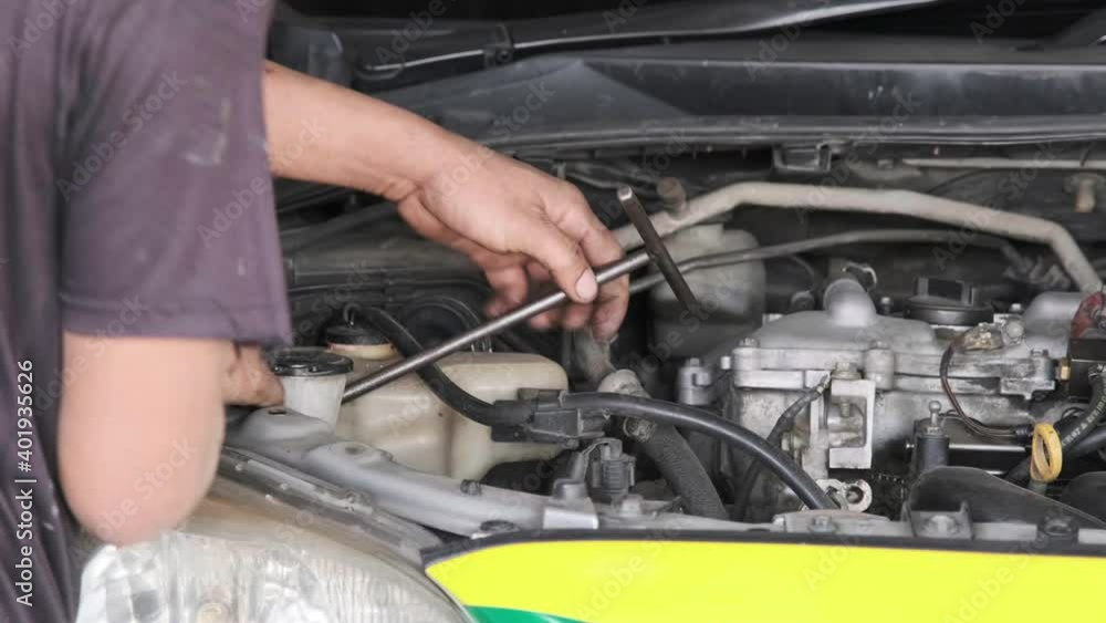 A maintenance worker using a t wrench torque tighten the car engine nut A maintenance worker using a t wrench torque tighten the car engine nut