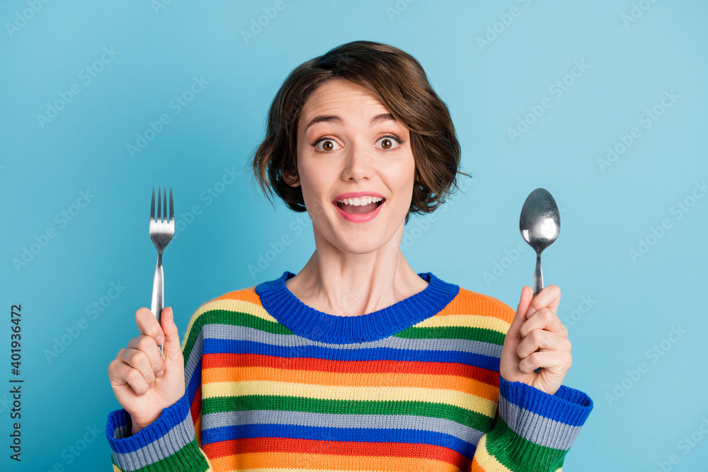 Portrait of lovely cheerful girl holding fork spoon waiting domestic tasty delicious dinner isolated over bright blue color background Portrait of lovely cheerful girl holding fork spoon waiting domestic tasty delicious dinner isolated over bright blue color background