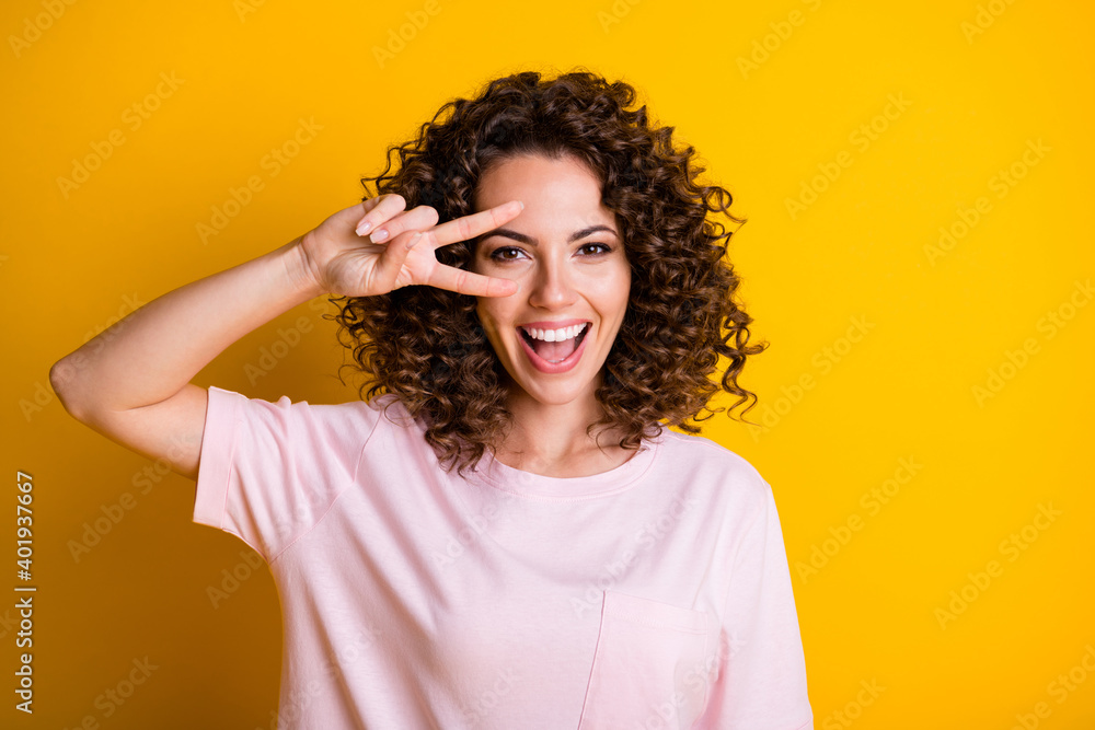Photo portrait of girl showing v-sign near eye isolated on vivid yellow colored background Photo portrait of girl showing v-sign near eye isolated on vivid yellow colored background