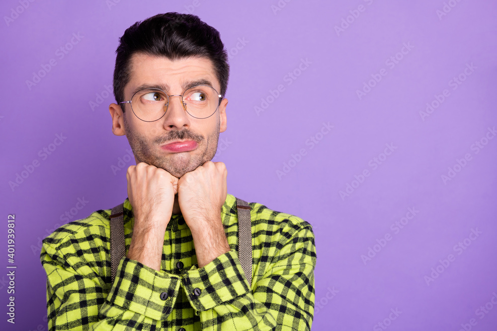 Photo portrait of bored guy holding head with fists looking at blank space isolated on vivid violet colored background Photo portrait of bored guy holding head with fists looking at blank space isolated on vivid violet colored background