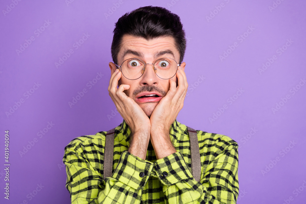 Photo portrait of scared man touching face cheeks with two hands isolated on vivid violet colored background Photo portrait of scared man touching face cheeks with two hands isolated on vivid violet colored background