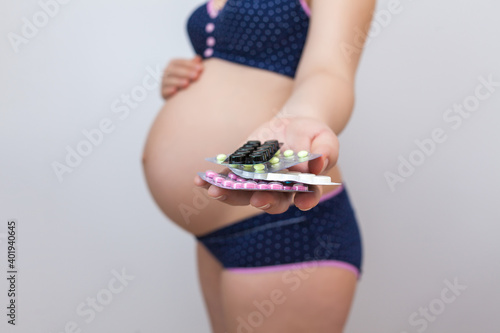 Vitamins in the hand of a pregnant woman. White background