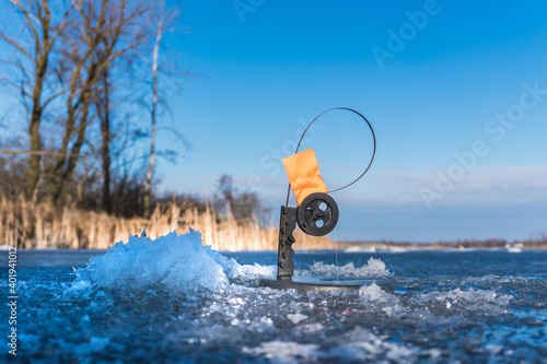 Winter fishing rod, tip-up with reel and orange flag tackle.