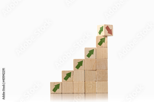 Stacked wooden cube blocks with printed arrows pointing up and another block twisting on top showing up and down arrows. Uncertainty and risk management concept.