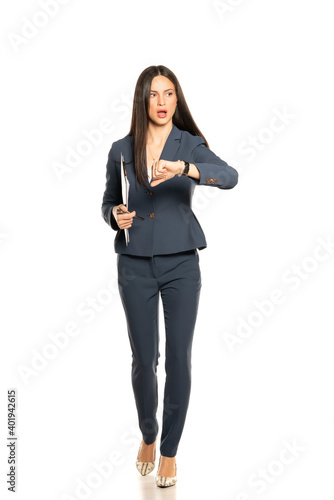 Young shocked business woman looking in her wristwatch and run