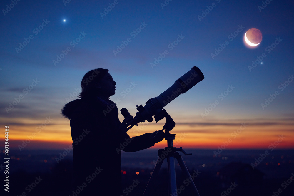 Child girl observing stars, planets, Moon and night sky with astronomical telescope.