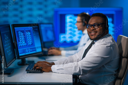 Call-center worker is speaking with the client by headset. Workplace of the african-american support operator.