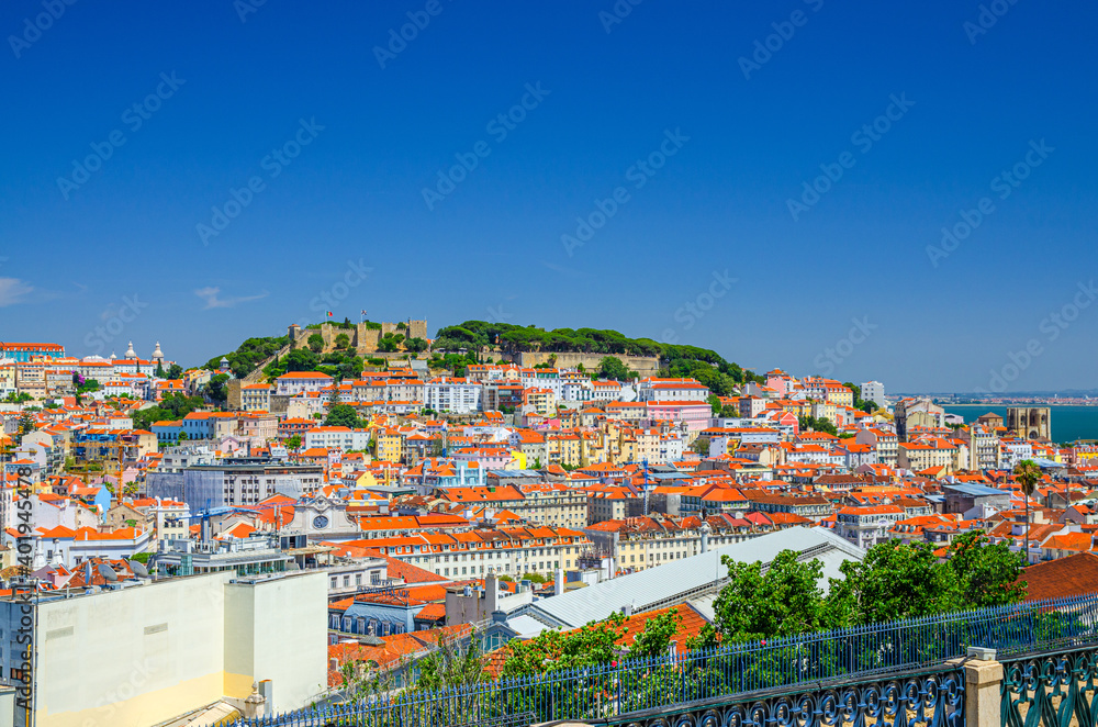 Lisbon cityscape, aerial panoramic view of Lisboa historical city centre with colorful buildings red tiled roofs, Sao Jorge Castle on hill and neighborhoods of Castelo, Mouraria and Alfama, Portugal.