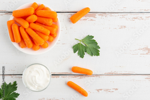 Small peeled pieces of carrot in plate on white wooden table. Top view. Copy space. © Grigoriy