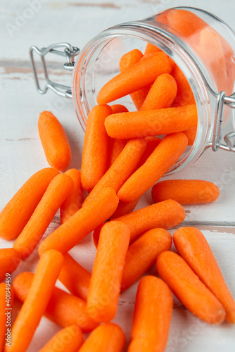 Glass jar with small peeled pieces of carrot on white wooden table photo