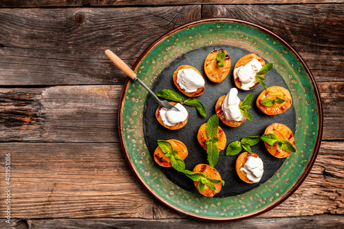 Delicious grilled peaches served with whipped cream and mint leaves. Grilled peaches, apricots, nectarines and ice cream
