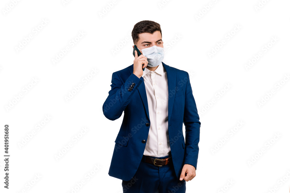 Young businessman with protective mask talking on the mobile phone on a white background Young businessman with protective mask talking on the mobile phone on a white background