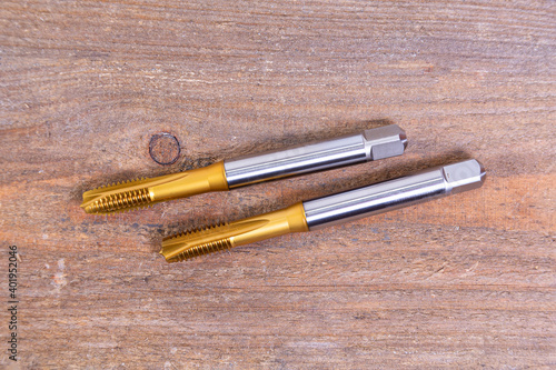Metal threading taps. Tool for processing metal on a wooden board.