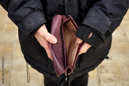 An elderly homeless poor woman holds an empty wallet, or purse. The concept of poverty in retirement. Global Extreme poverty. No money help me. Covid-19 Global Financial Crisis.