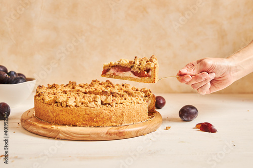 фотографія A closeup shot of a hand taking a slice of delicious plum cake