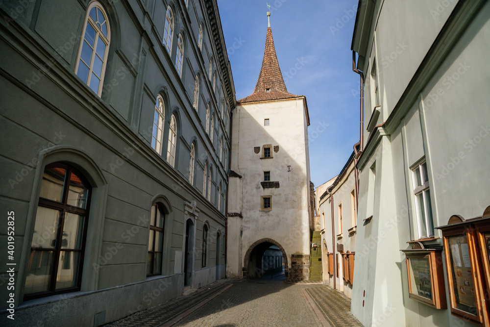 Obraz premium Gothic tower of the Velvary Gate, town fortifications built in the pre-Hussite period in sunny day, street of historic medieval city Slany, Central Bohemia, Czech Republic