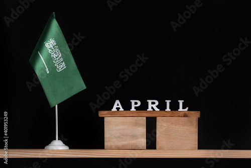 Wooden calendar of April with Saudi Arabia flag on black background. Dates of Saudi Arabia in April