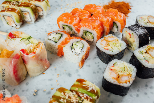 Close up view on assorted Japanese sushi food and rolls on bright table, chopsticks and ingredients