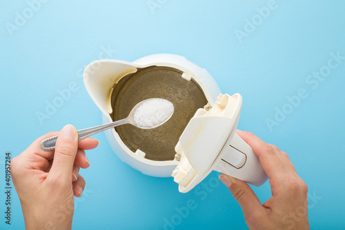 Bild auf Leinwand Young adult woman hand holding spoon with white powder of citric acid for descaling kettle