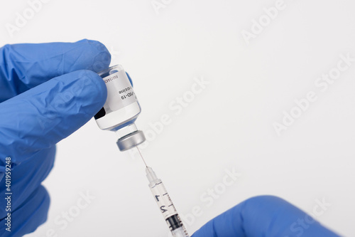 Close up human fingers in gloves, holding covid-19 vaccine vial  and syringe with needle. Medical concept.