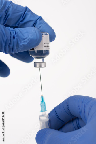Close up human fingers in gloves, holding covid-19 vaccine vial and syringe with needle. Medical concept.