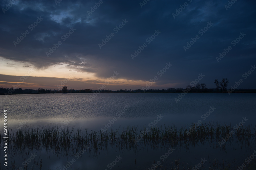 Dark evening clouds at the lake with reeds Dark evening clouds at the lake with reeds