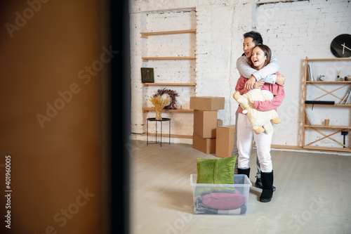 Comfort. New property owners, young couple moving to new home, apartment, look happy. Dream, love, relationship, real estate and interior concept. New life. Caucasian woman and asian man.