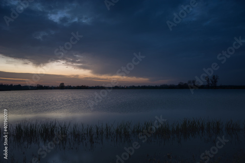 Dark evening clouds at the lake with reeds