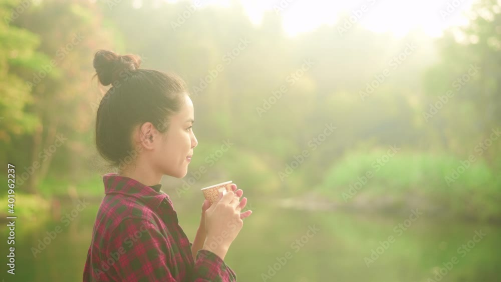 A beautiful young traveler woman is enjoying with nature drinking coffee in the morning over lake, relaxation , camping holiday and travel concept . A beautiful young traveler woman is enjoying with nature drinking coffee in the morning over lake, relaxation , camping holiday and travel concept .