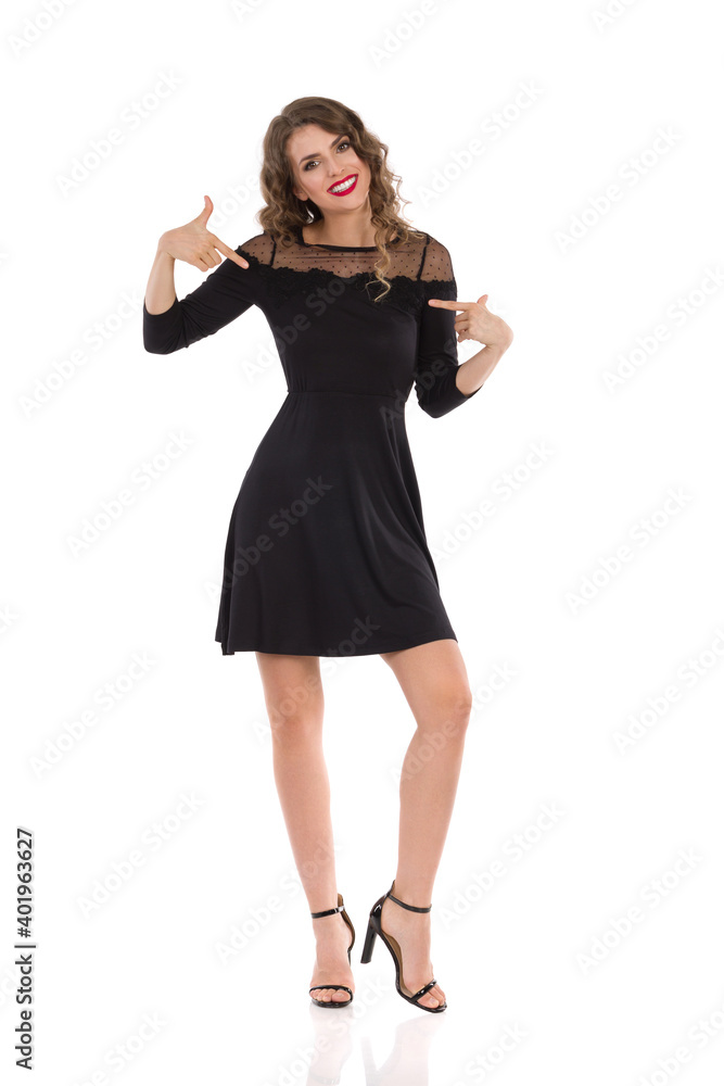 Confident Young Woman In Elegant Black Dress And High Heels Is Pointing At Herself Confident Young Woman In Elegant Black Dress And High Heels Is Pointing At Herself
