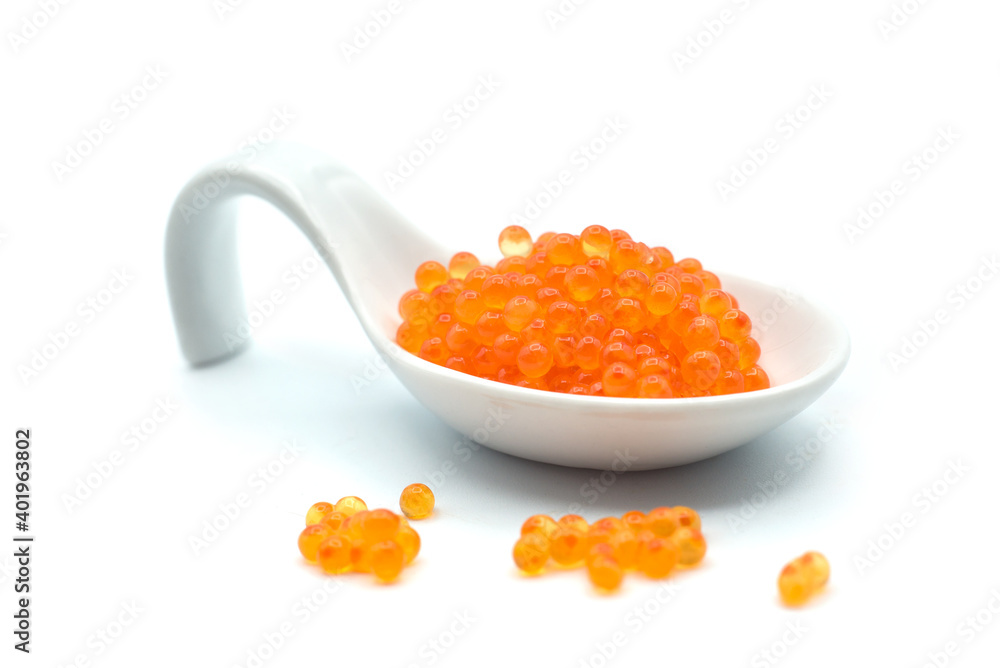 Closeup of trout eggs in a white ceramic spoon on white background Closeup of trout eggs in a white ceramic spoon on white background