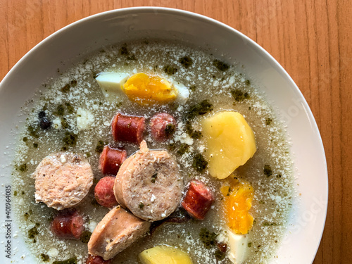 Traditional Polish soup Zurek with eggs, white and red sausages.