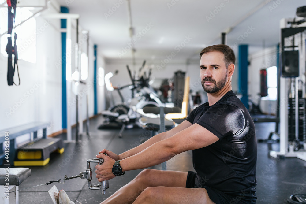 Young man Doing Heavy Weight Exercise For Back On Machine, Focus on him. Concept of health. Fitness Young man Doing Heavy Weight Exercise For Back On Machine, Focus on him. Concept of health. Fitness