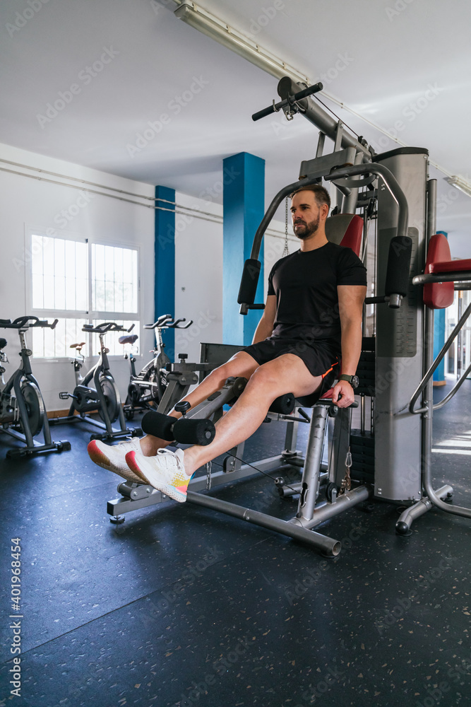 Handsome man doing leg exercises in a gym. Vertical Handsome man doing leg exercises in a gym. Vertical