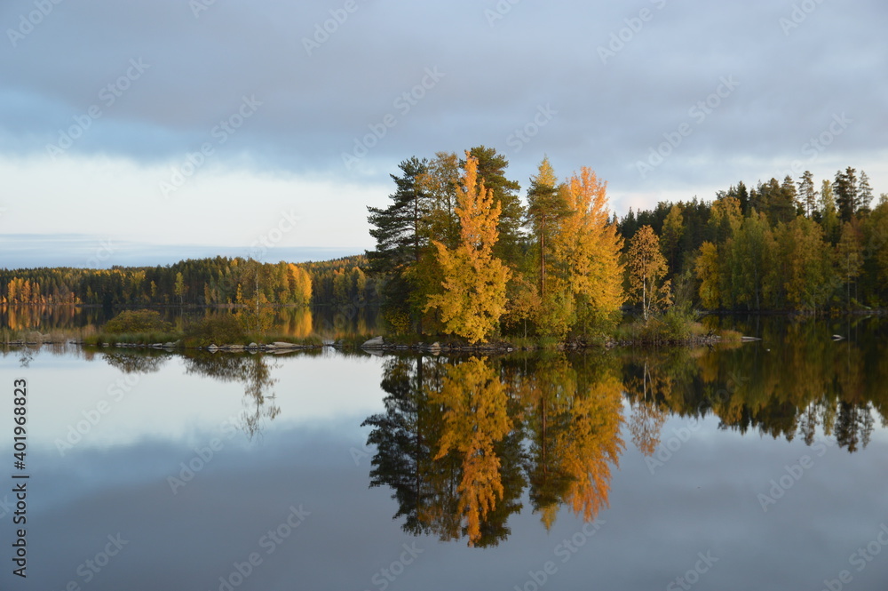 Serene Finnish lake with trees turning in to autumn colors