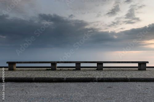bench in front of a sky with clouds photo