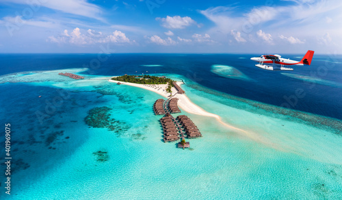 Fototapeta Naklejka Na Ścianę i Meble -  A seaplane is approaching a tropical paradise island in the Maldives with turquoise sea and sunshine