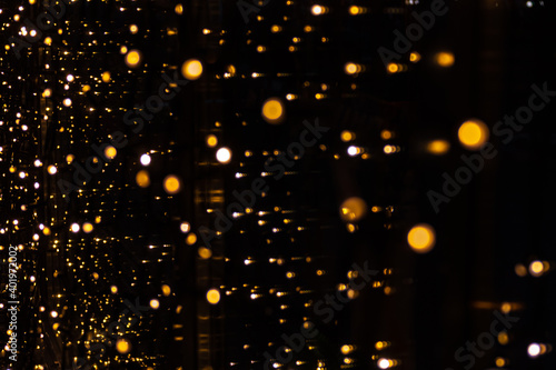 Perfect bokeh for a festive New Year and Christmas background. Defocused abstract circles of yellow and blue light on windows © Alena