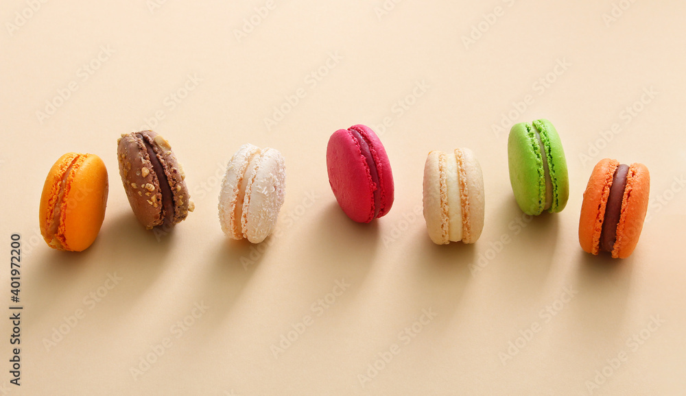 Obraz premium Colorful french macaroons on beige background. Almond cookies.Top view, flat lay. Valentine's day sweet gift concept,holiday, celebration.