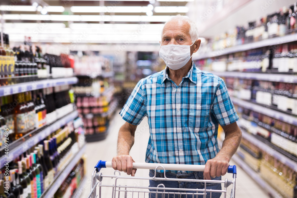 older european man wearing mask and gloves with covid protection shoping in supermarket