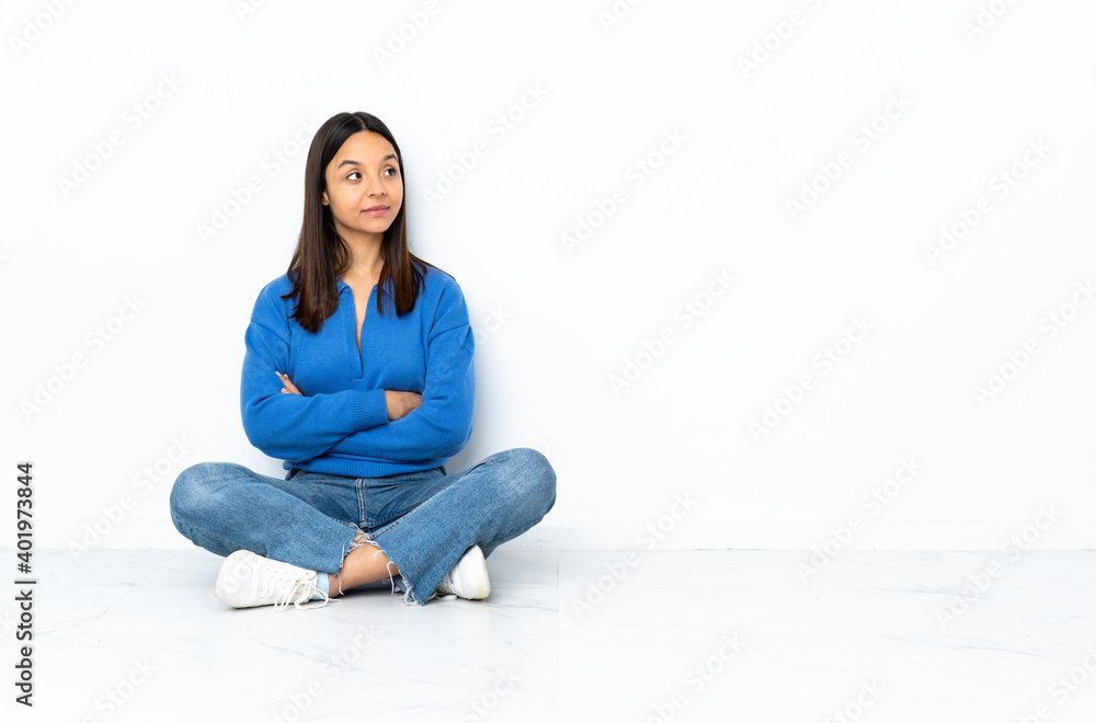 Young mixed race woman sitting on the floor isolated on white background in back position and looking back Young mixed race woman sitting on the floor isolated on white background in back position and looking back